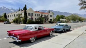 Classic cars parked on US-395 in Independence, CA. Historic Winneduma Hotel across the street. Sierra Nevada mountains in the background.