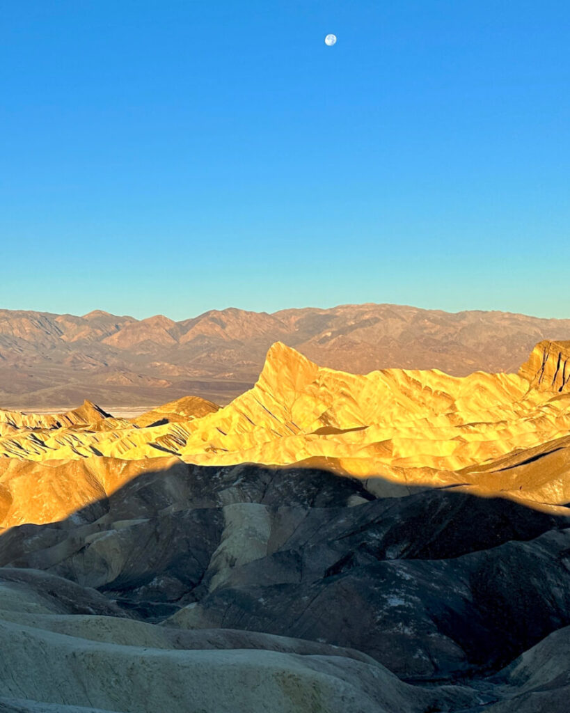 Golden sunrise and setting moon over Manly Beacon in Death Valley National Park.