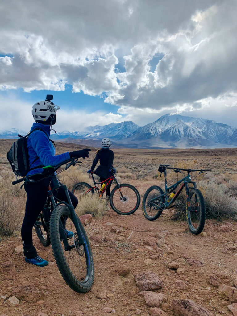 Mountain bikers on the Tablelands, looking at the snow covered Mt. Tom, an Eastern Sierra experience near Bishop.